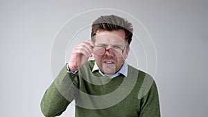 European young man with poor vision peers through his glasses, trying to discern the information that interests him