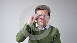 European young man with poor vision peers through his glasses, trying to discern the information that interests him