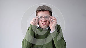 European young man with poor vision peers through his glasses, trying to discern the information that interests him