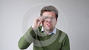 European young man with poor vision peers through his glasses, trying to discern the information that interests him photo