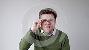 European young man with poor vision peers through his glasses, trying to discern the information that interests him photo