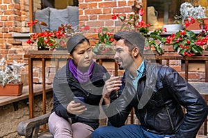 European young man talking to an asian girl holding a smartphone