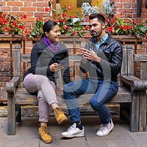 European young man talking to an asian girl holding a smartphone