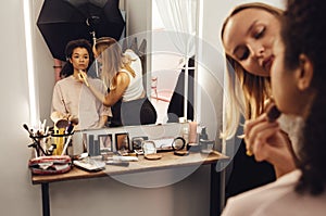 European young professional makeup artist applies foundation to female client skin