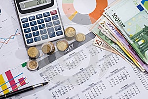 Euros bills, calendar, pen and calculator.