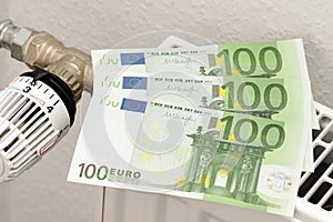 300 euros lie on the heating radiator. Three paper banknotes of 100 euros each. A symbol of rising heating costs.