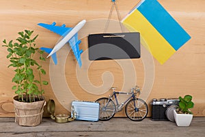 Eurovision 2017 concept - blank blackboard, flag of the Ukraine, airplane model, little bicycle and suitcase, camera, compass