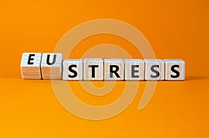 Eustress or stress symbol. Turned wooden cubes and changed the concept word Eustress to Stress. Beautiful orange table orange