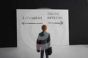 Euthanasia versus endless suffering concept with miniature man and arrows. Legalization of assisted suicice for some patients