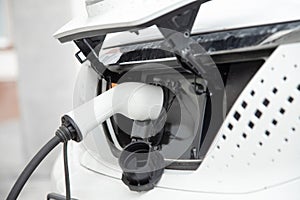 EV Car or Electric car at charging station with the power cable supply plugged . Close up view