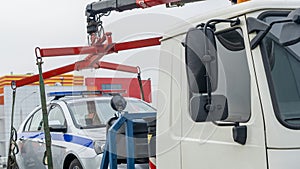 Evacuation of the broken police car with red and blue flasher. A broken police car stands on a tow truck.