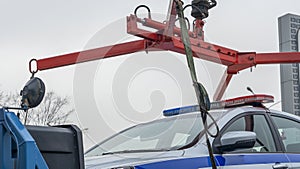 Evacuation of the broken police car with red and blue flasher. A broken police car stands on a tow truck