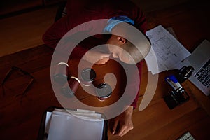 Even the coffee couldnt keep him awake. High angle shot of a young man asleep at his desk while working late in the