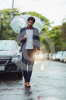 Even the rain wont deter him. Full length shot of a handsome young businessman on his morning commute in the rain.