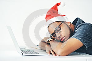 Even Santa needs to take a break. a young businessman sleeping on his desk while working in his office on