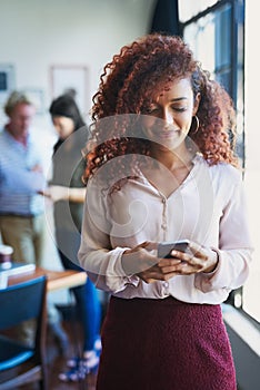 Even smartphones are used to manage business. a young woman using a mobile phone with her team in the background of a