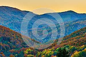 Večerní podzimní horská krajina s výhledem na osamělé domy do barevného údolí s lesem. Dúbrava, Slovensko.