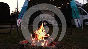 Evening bonfire close-up on the background of a motorhome. The dog is sitting near the fire