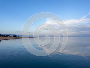 Evening calm and smooth lake surface under soft clouds