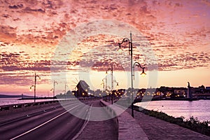 Evening city landscape - view of the road with street lights and the wooden windmill before the entrance to the Old Town of Nesseb