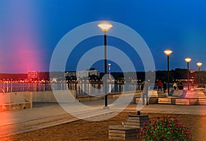 Evening city promenade people walk and relax street lamp light on pier  blurred on sea water in port of Tallinn Reidi tee