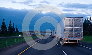 Evening convoy semi trucks trailers on straight interstate highw