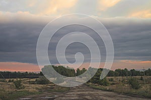 Evening country dirt road fork. Bad roads in the rural hinterland. Rustic Cloudy Sunset Landscape