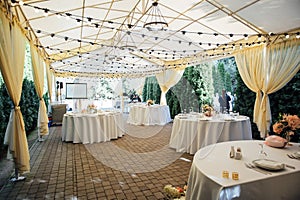 Evening decoration of a wedding party. Tables for guests with a garland and lamps
