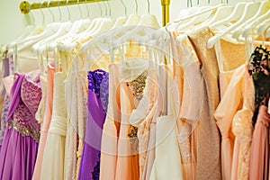 Evening elegant dresses on a shop window of a fashion boutique and on a hanger of a store for sale