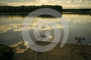 Evening fishing. Fishing rods on wooden pier on pond
