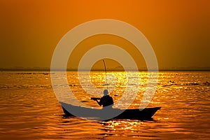 Evening golden sunset time, a fisherman fishing on the seaside on a boat