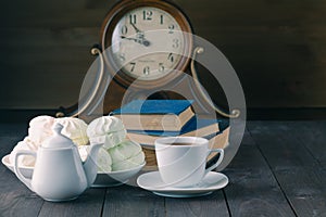 Evening with hot tea, sweets and books on wood table