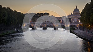 Evening illumination of ponte Sisteo and St. Peter`s basilica in Rome, Italy