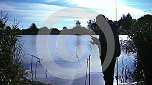 Evening Lakeside: Man Collecting Fishing Gear after a Day of Fishing