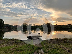 Evening landscape on a lake in the forest. Sunset on the pond. Fishing platform on the river