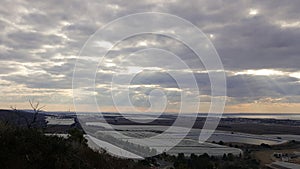 Evening landscape view on Mediterranean Sea coastline, sky, clouds, valley with water reservoir and orangeries