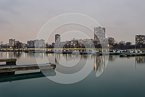 Evening lighting over calm water with empty boat docks and apartment highrises photo