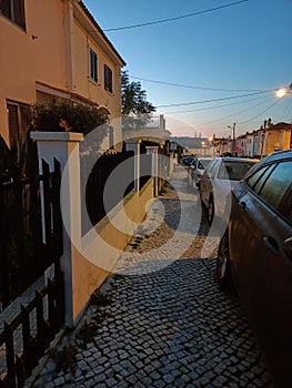 Evening in Lisbon. Cars are parked on the sidewalk. City lighting has already been turned on photo