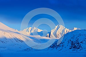 Evening mountain. White snowy mountain peak, blue glacier Svalbard, Norway. Ice in ocean. Iceberg in North pole. Beautiful landsca