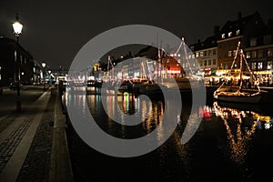 Evening Nyhavn, ships, festive illumination, reflection in the dark water of the canal. Copenhagen, Denmark.