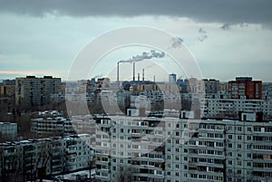 Evening panorama of the city with a view of the residential buildings and the smoking pipes of the thermal power plant.