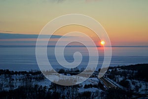 Evening panorama of the embankment of the frozen Volga River against the backdrop of a stunning sunset sky and clouds.