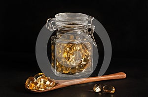 Evening primrose capsules in a glass jar and on a wooden spoon