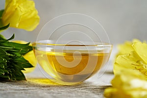 Evening primrose oil in a bowl with fresh Oenothera biennis flowers