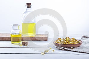 Evening primrose oil in capsules and in bottles, on a white wooden base. Health care concept