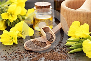 Evening primrose seeds and oil in glass bottle with flowers