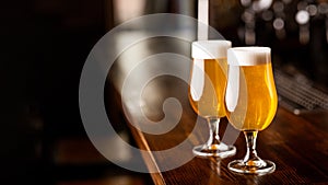 Evening at pub. Glasses with beer and foam on wooden brown bar counter in pub