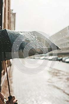 Evening rain and black umbrella against the background of a deserted city street. Closeup view