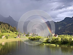 Evening rainbow after the spring downpour over meadows and pastures in the Sihltal valley and by the artifical Lake Sihlsee
