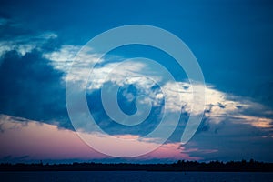 Evening river landscape. Calm water and dramatic sky with clouds